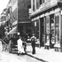<p>This image is an enlarged portion of another photograph appearing here. Two men are shown unloading a horse-drawn wagon on Centre St. at the corner with Burroughs St. The store in the foreground is F.A. Keazer Groceries and Provisions, seller of fruits, vegetables, other foods, and supplies. The storefront with the prominent sign next to F.A. Keazer is the C.B. Rogers & Co.  The F. A. Keazer building was demolished and the property remained undeveloped for many years. A new building was built at the location, 697 Centre St., in 1998 and the Wonder Spice Restaurant has occupied it since April 1999. The C.B. Rogers & Company building is currently occupied by Bukhara (an Indian restaurant), a rare book dealer, and other offices. Today’s Bread, a cafe, preceeded Bukara from the early 1980s to the late 1990s. Before Today’s Bread, the building was home to Hanlon’s Shoes. The four-story brick building seen to the far left of the photograph, on the opposite side of the street is the apartment building at 745 Centre St. at the corner with Greenough Ave.</p><br/>