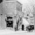 This image is an enlarged portion of another photograph appearing here. A horse and buggy is shown at the corner of Centre and Myrtle Streets. The corner building, site of the current day post office building, 655 Centre St., displays signs for a hardware store and M.T. Wallace Groceries. The firehouse, at 659 Centre St., at the far left, looks much like it does today. The firehouse is the current home of J.P. Licks. The Baptist Church on the far side of Myrtle St. is out of view but the house at 629 Centre can be seen beyond it.